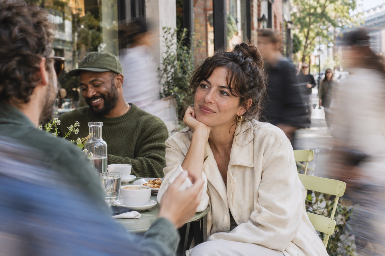 A focused conversation at a Brooklyn cafe, surrounded by blurred passers-by